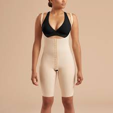 a woman in a bodysuit standing in front of a beige background